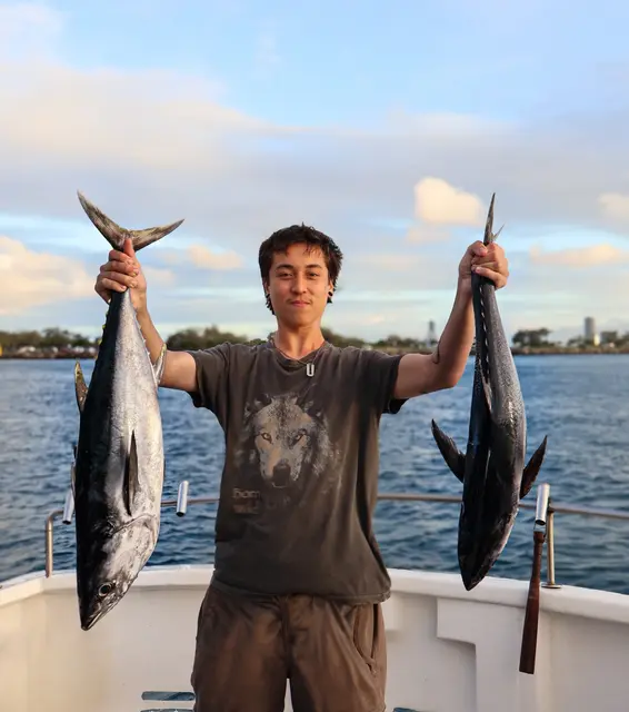 Angler on an Australian offshore fishing charter holding two large tuna