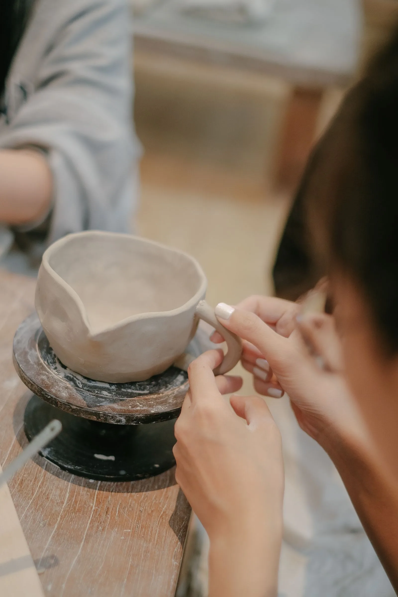 Hands holding a clay pitcher for a pottery class