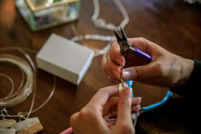 Hands making jewelry with pliers in a workshop